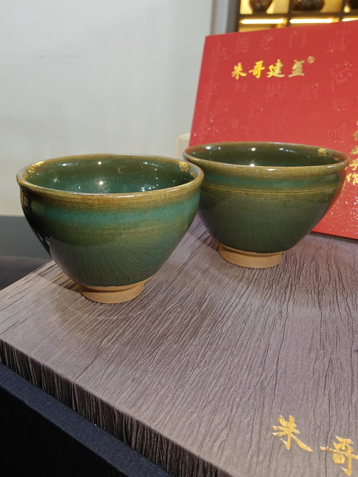 Teal green JianZhan tea cup pair exterior view showing deep green glaze with gold rim