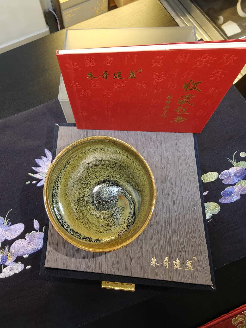 Olive-gold conch shell JianZhan tea bowl interior — swirling silver galaxy with amber-red base