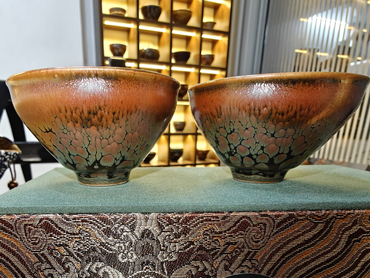 百花 Hundred Flowers pair JianZhan tea bowls exterior view showing warm amber-brown glaze with crackle flower pattern